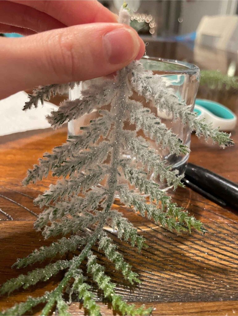 faux tree branch pressed against glass votive
